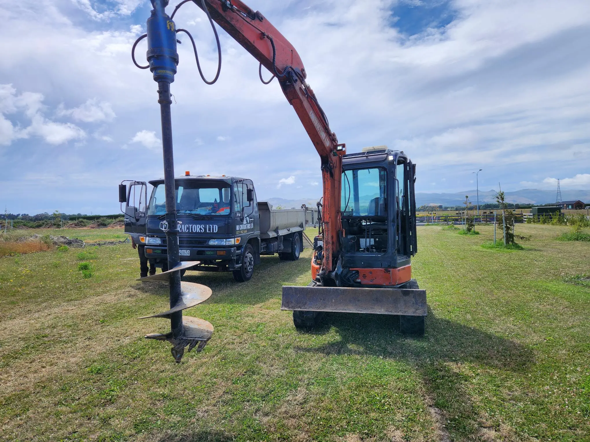 Orange Hitachi excavator with auger and 3.5t tipper on a Canterbury job