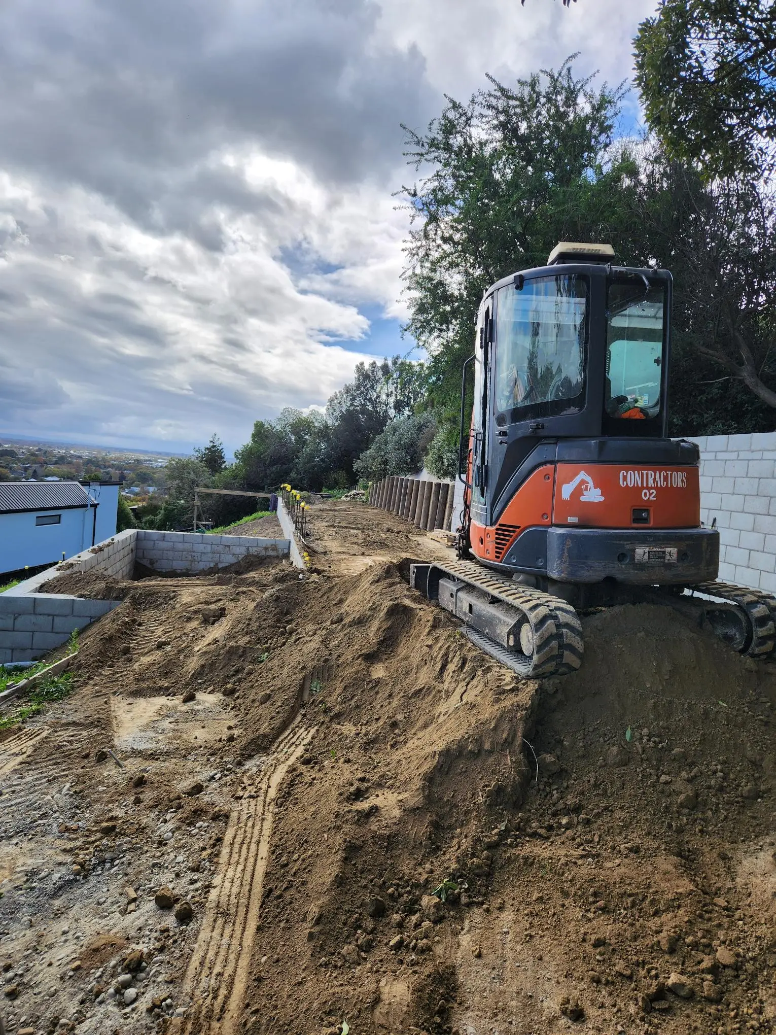 Digger at the top of a freshly scraped and levelled hillside cut