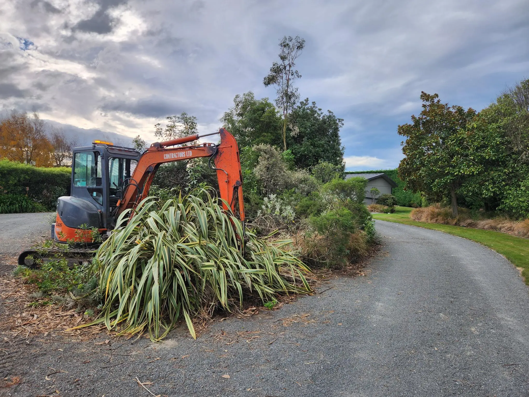 Digger on a coastal residential site under clear blue skies with the harbour beyond